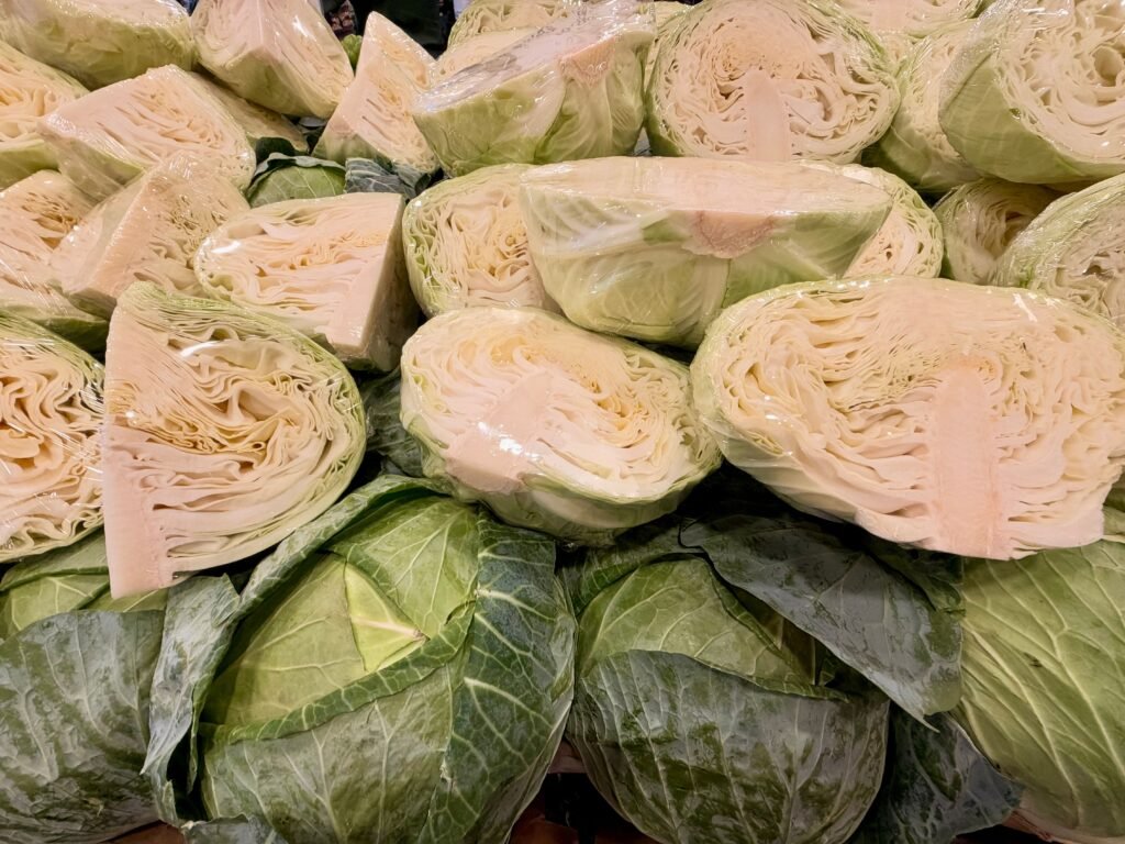A vibrant stack of halved cabbages wrapped in plastic at a market in Tarneit, Victoria.